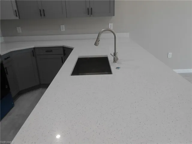 Kitchen with gray cabinets and light stone counters