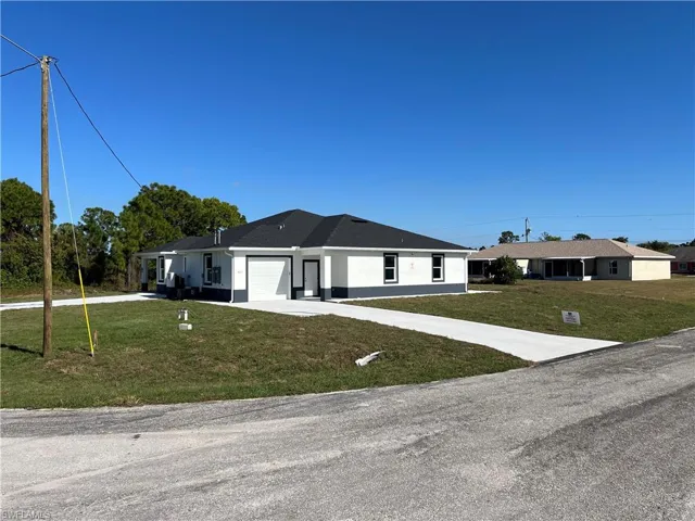 Single story home featuring a front lawn, stucco siding, concrete driveway, and a garage