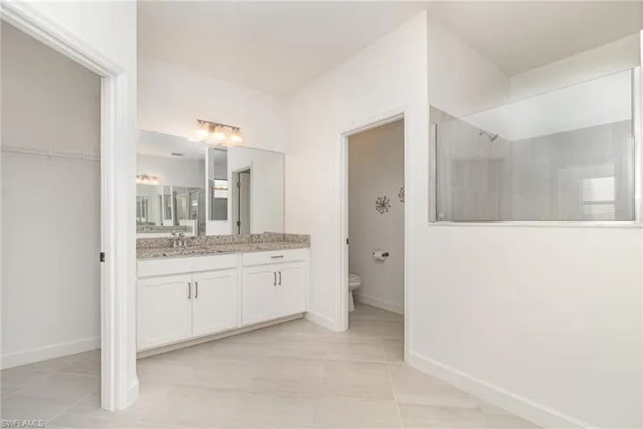 Bathroom with vanity, a walk in shower, and light tile patterned floors
