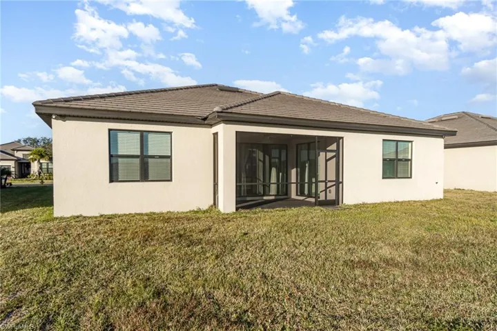 Back of house with stucco siding, a lawn, and a sunroom
