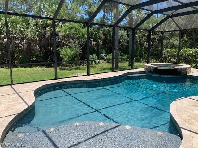 View of pool with screen enclosure and the in ground hot tub