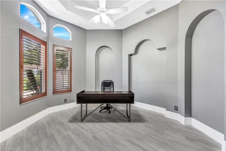 Office area with ceiling fan, a tray ceiling, and hardwood / wood-style flooring