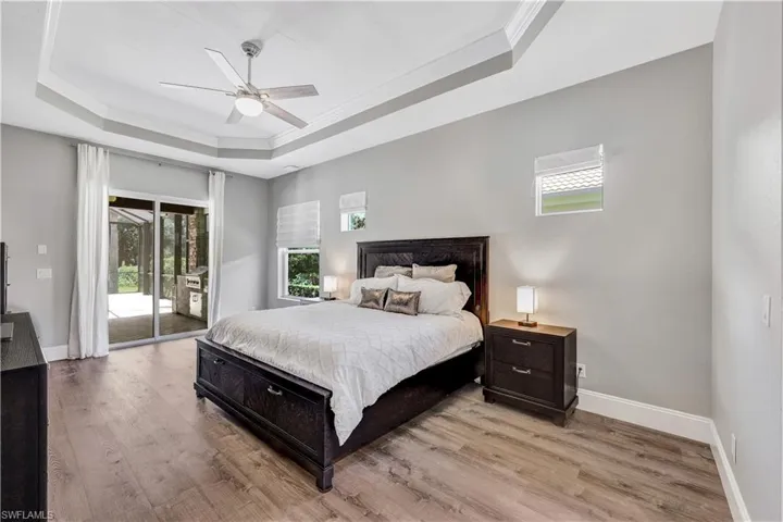 Bedroom featuring access to outside, ceiling fan, a raised ceiling, crown molding, and light wood-type flooring