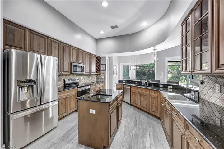 Kitchen featuring tasteful backsplash, an island with sink, stainless steel appliances, dark stone countertops, and sink