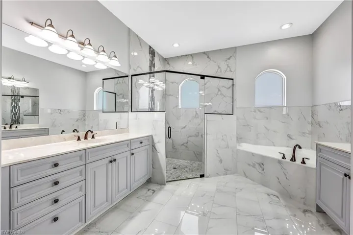 Bathroom with a wealth of natural light, vanity, tile floors, and plus walk in shower