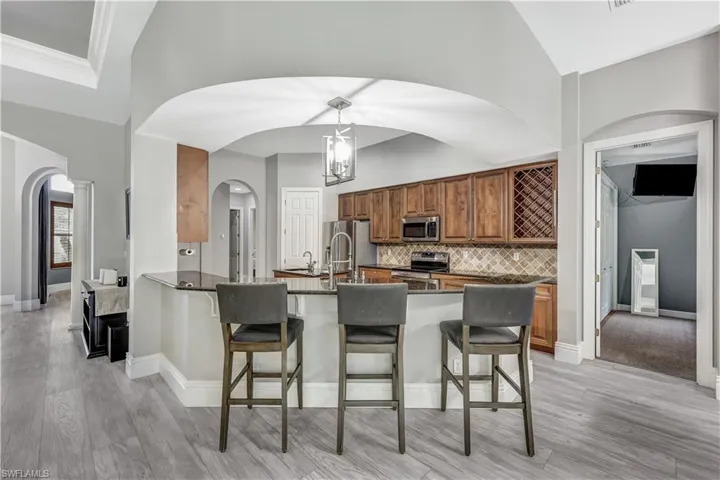 Kitchen featuring kitchen peninsula, tasteful backsplash, stainless steel appliances, light wood-type flooring, and a kitchen bar