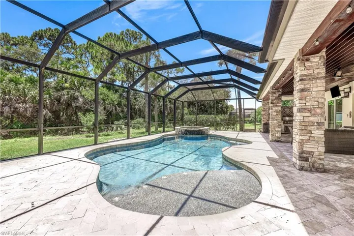 View of swimming pool with glass enclosure, an in ground hot tub, and a patio