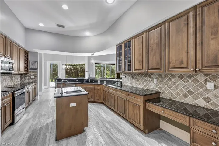 Kitchen featuring a kitchen island, light hardwood / wood-style flooring, stainless steel appliances, backsplash, and sink
