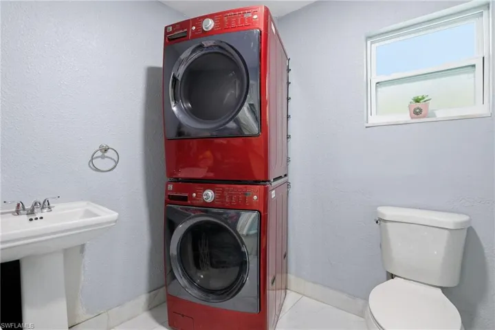 Bathroom with a textured wall and stacked washer and clothes dryer