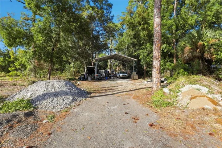 View of yard featuring a carport, view of scattered trees, and driveway