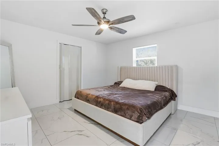 Bedroom with ceiling fan, a closet, and light marble finish floors