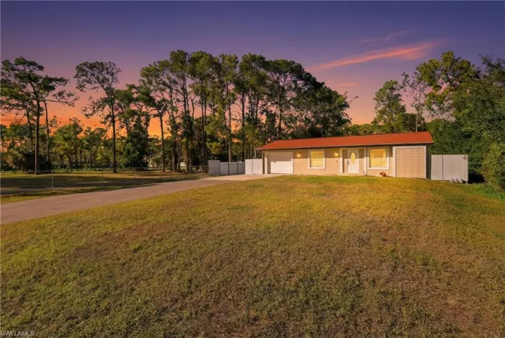 Single story home with concrete driveway and view of scattered trees