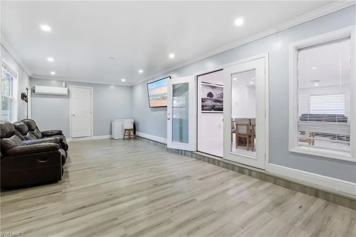 Living area with plenty of natural light, crown molding, light wood finished floors, and recessed lighting