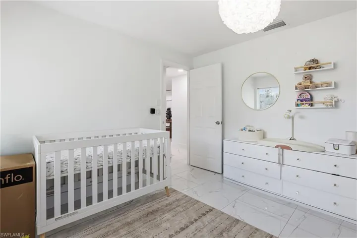 Bedroom with light marble finish floors and a crib