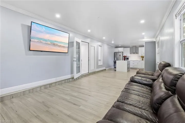 Living room with crown molding, light wood-style floors, and recessed lighting