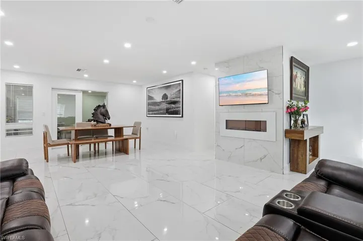 Living room with recessed lighting, a fireplace, and light marble finish flooring