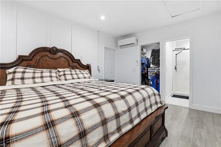 Bedroom featuring light wood-style floors, a spacious closet, ensuite bath, and recessed lighting