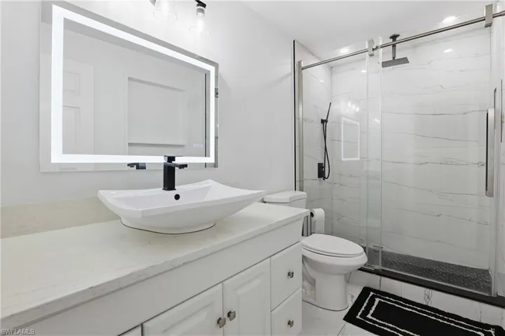 Full bathroom featuring a marble finish shower and vanity