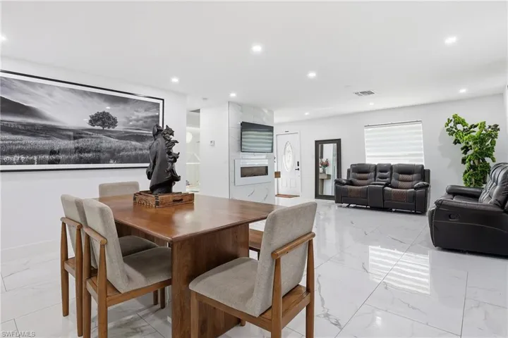Dining space with a fireplace, recessed lighting, and light marble finish floors