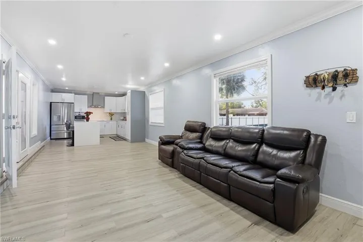 Living area featuring crown molding, light wood-type flooring, and recessed lighting