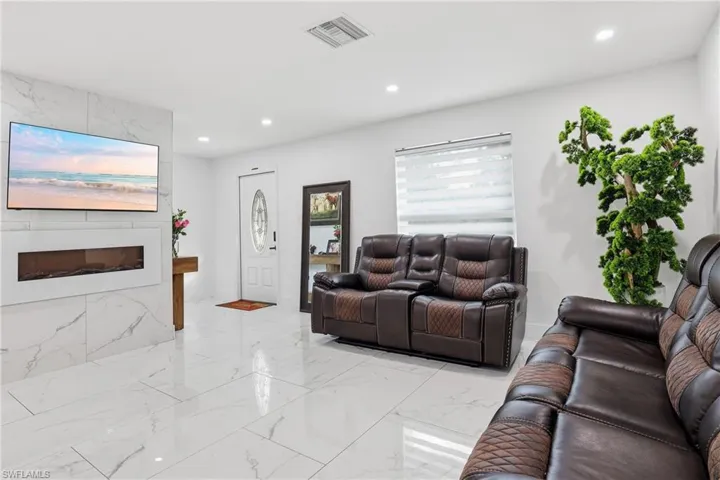 Living room with a premium fireplace, recessed lighting, and light marble finish flooring