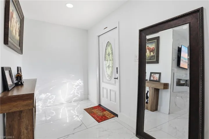 Entrance foyer with light marble finish floors and recessed lighting