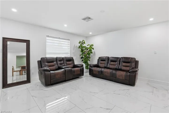 Living area featuring recessed lighting and light marble finish flooring