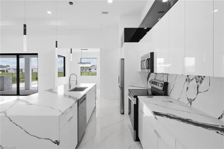 Kitchen featuring sink, decorative light fixtures, appliances with stainless steel finishes, light tile patterned floors, and plenty of natural light