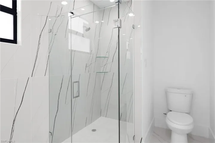 Bathroom featuring tile patterned flooring, toilet, and an enclosed shower