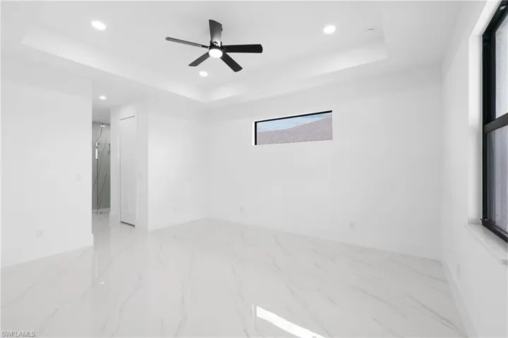 Empty room featuring light tile patterned floors, a raised ceiling, and ceiling fan
