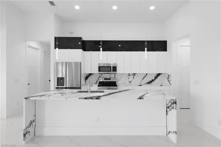 Kitchen with white cabinetry, light tile patterned floors, stainless steel appliances, and a spacious island