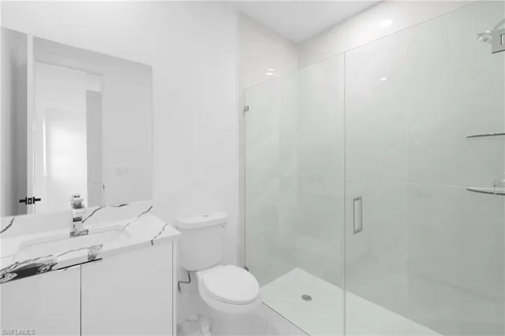 Bathroom with an enclosed shower, vanity, and toilet