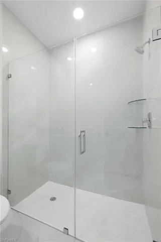 Bathroom featuring tile patterned floors, toilet, and a shower with door