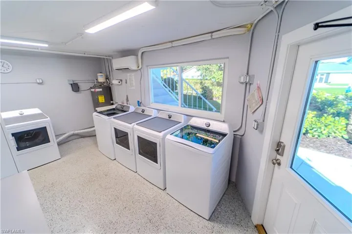 Laundry area featuring dark aggregate flooring, independent washer and dryer, and water heater