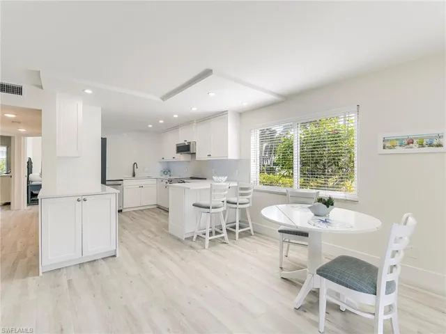 Kitchen featuring a peninsula, a kitchen breakfast bar, white cabinets, stainless steel appliances, and light wood-type flooring