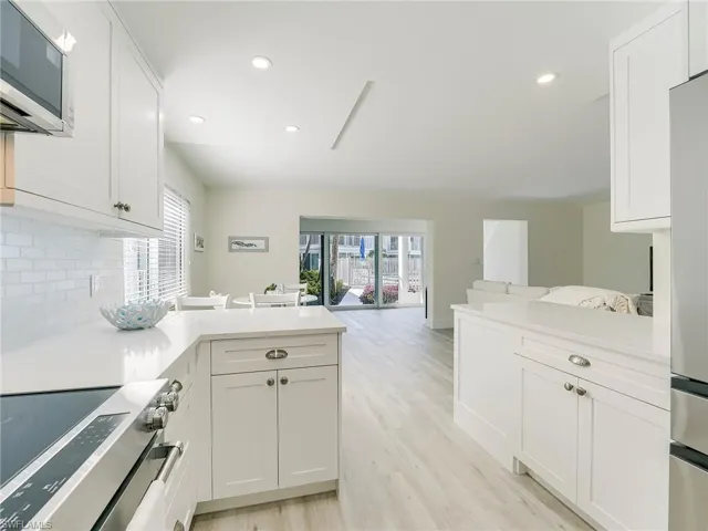 Kitchen with a peninsula, stainless steel appliances, white cabinetry, and recessed lighting