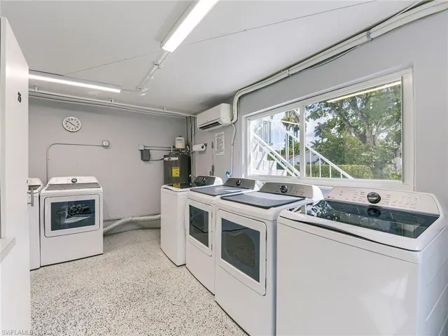 Laundry area featuring washer and clothes dryer, electric water heater, and dark speckled floor