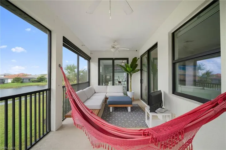 Screened lanai featuring a ceiling fan, a large window, and sliding glass doors