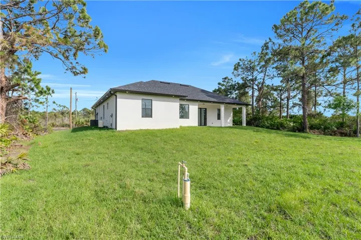 Back of house with stucco siding and a yard