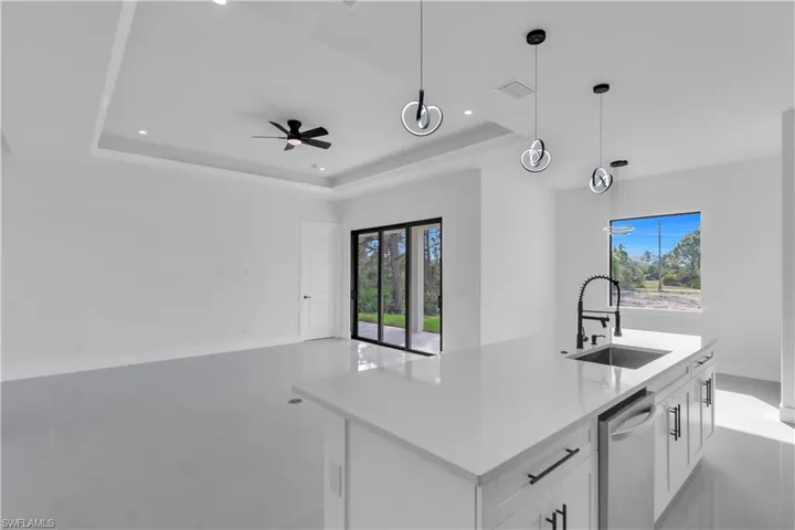 Kitchen with visible vents, white cabinets, a raised ceiling, a sink, and stainless steel dishwasher