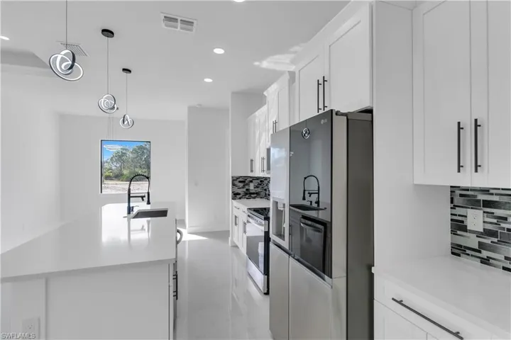 Kitchen with stainless steel appliances, visible vents, a sink, and white cabinetry