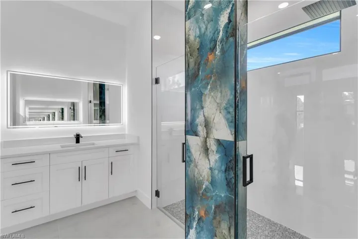 Bathroom featuring a stall shower, marble finish floor, and vanity