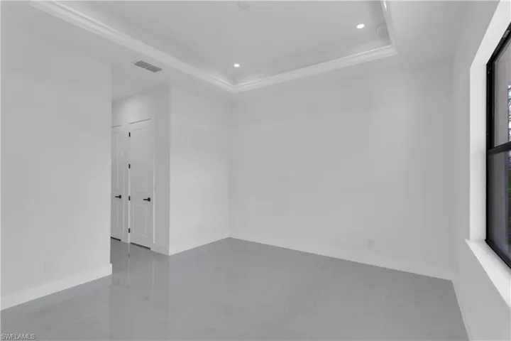 Empty room with baseboards, visible vents, a tray ceiling, and recessed lighting