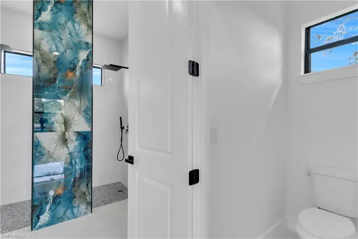 Full bath featuring walk in shower, toilet, and a healthy amount of sunlight