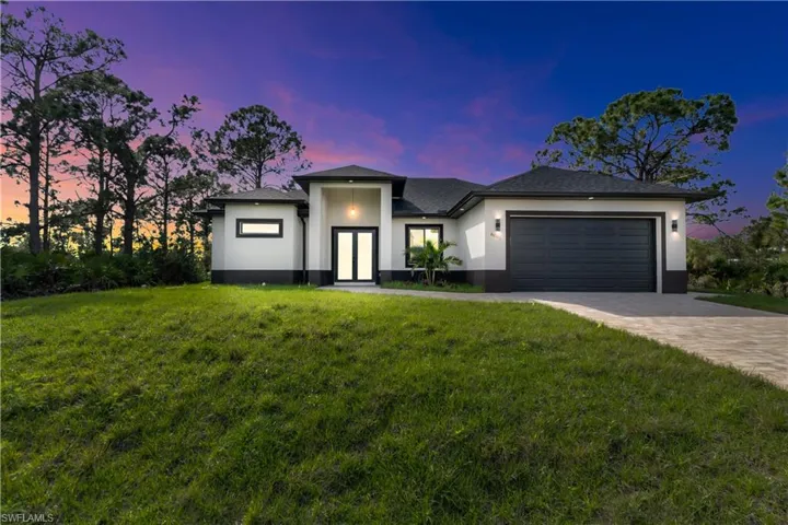 Prairie-style home featuring a garage, decorative driveway, a front yard, and stucco siding