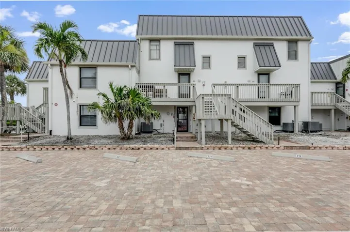 Back of house featuring stairway, stucco siding, and uncovered parking