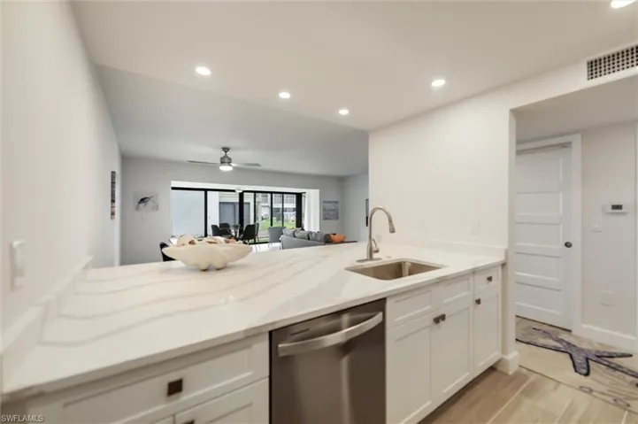 Kitchen with stainless steel dishwasher, a peninsula, white cabinets, a ceiling fan, and recessed lighting