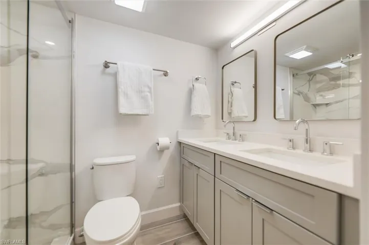 Full bathroom featuring double vanity and a marble finish shower