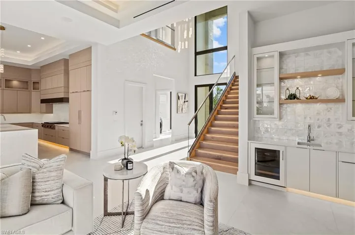 Living room with beverage cooler, stairway, wet bar, and a towering ceiling