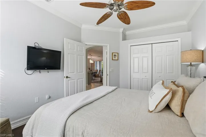 Bedroom with crown molding, ceiling fan, a closet, and wood finished floors